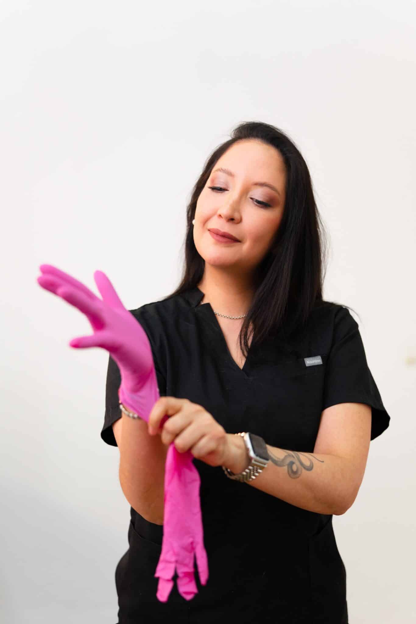 Dr. María Córdova zieht Handschuhe an, bevor sie eine professionelle ästhetische Behandlung durchführt.